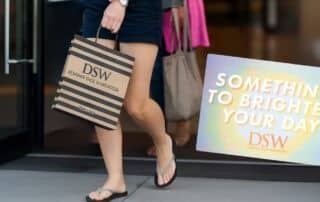 woman walking out of a store with a dsw shopping bag
