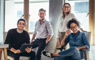 A group of 4 happy coworkers in a modern work environment.