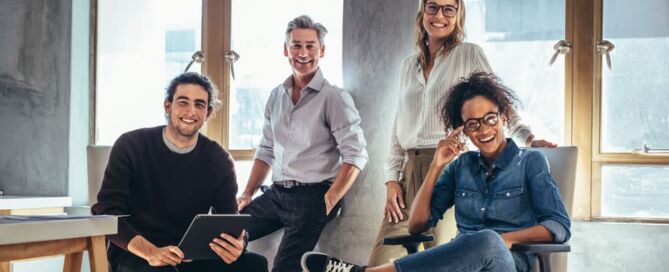 A group of 4 happy coworkers in a modern work environment.