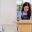 Concerned online store owner looking into a returned package with frustration, surrounded by shipping boxes and merchandise.